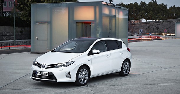Hvid Toyota Yaris kompaktvogn parkeret på grå asfaltkplads foran moderne bygning