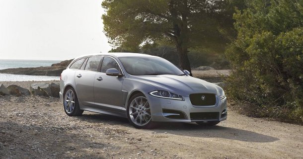 Sølvgrå Jaguar XF stationcar parkeret på grusvej med træer i baggrund