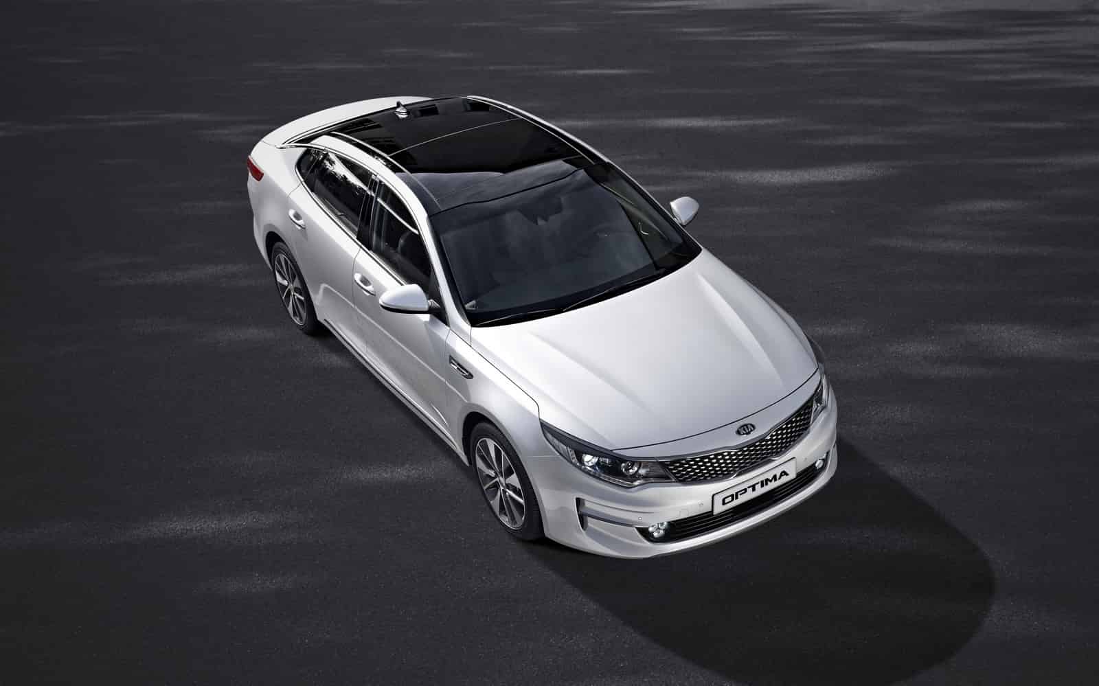 Hvid Kia Optima hybrid sedan fotograferet oppefra på grå asfaltergrund, viser siden og fronten af køretøjet