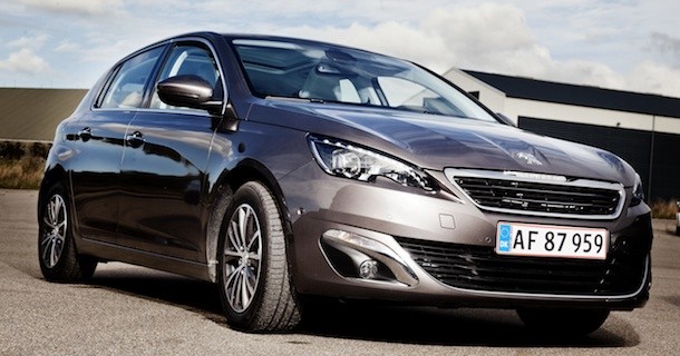 Grå Peugeot 308 hatchback med danske nummerplader parkeret foran industriel bygning