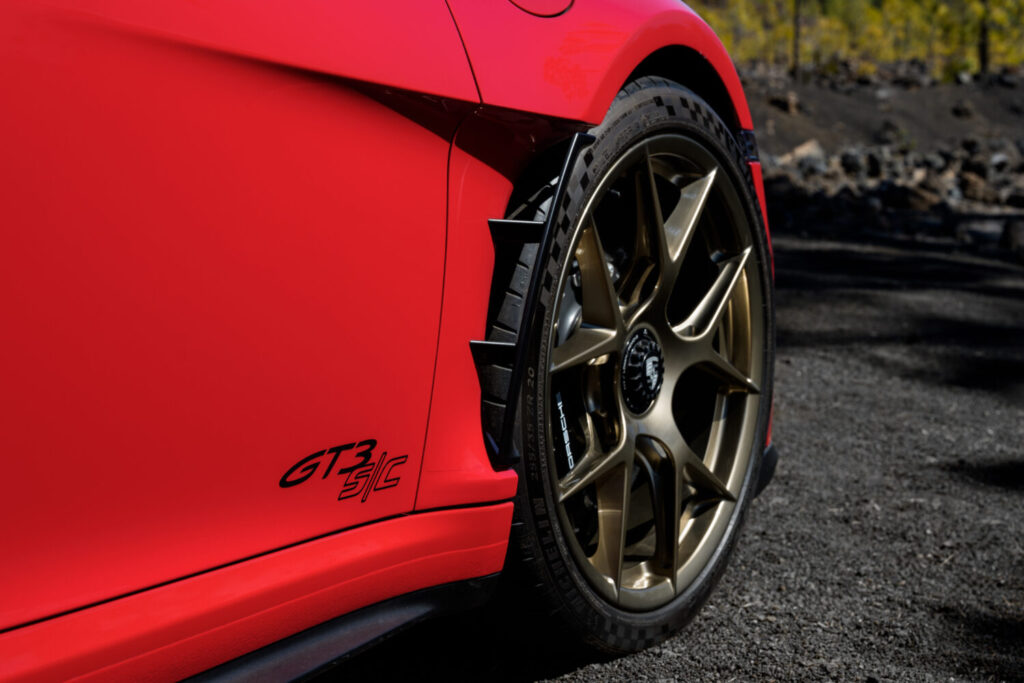 Nærbillede af baghjulet på en rød Porsche med guldfarvet fælg og synlig “GT3 RS” tekst på siden. Detaljen fremhæver bilens sporty design og performance i en kontekst der passer til Bilsektionen og Porsche.